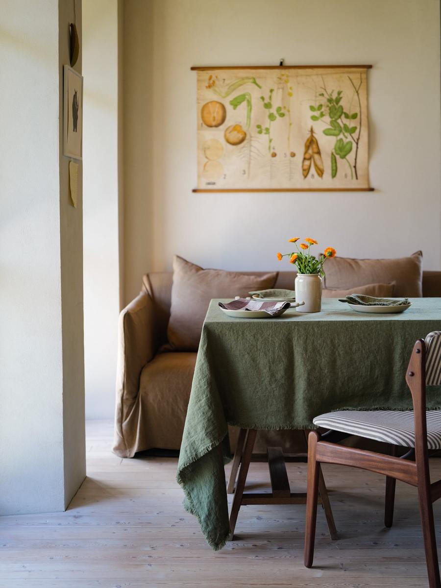 Olive Green Terra Fringe-hørdug med cremefarvede tallerkener og orange blomster