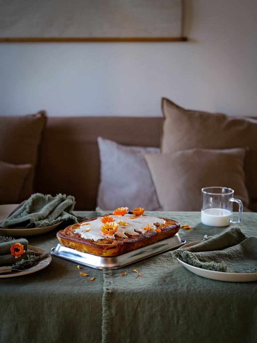 Kage med orange blomster på olivengrøn hør og frynsede servietter